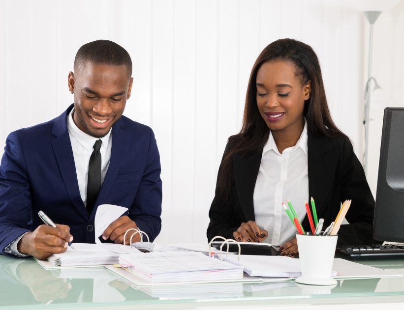 Two Happy Businesspeople Working On Business Document At Office